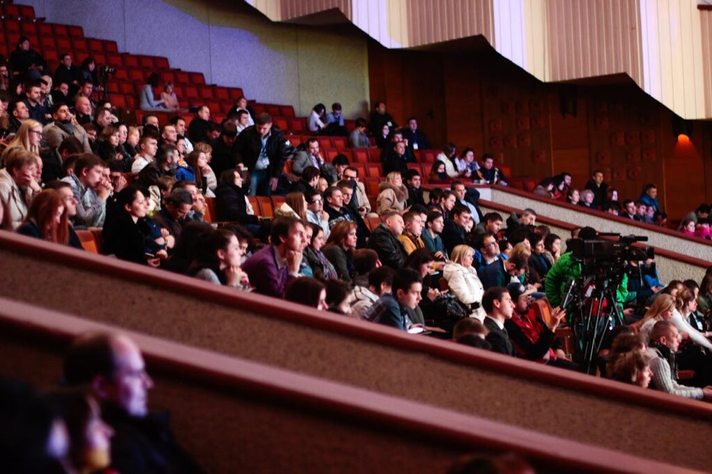 pexels-photo-301987 Engaged audience seated indoors, captured with a Canon camera. Ideal for event coverage visuals.